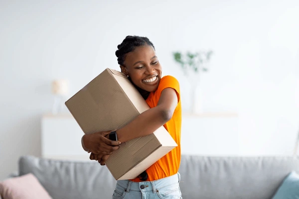 Cheerful woman hugging carton